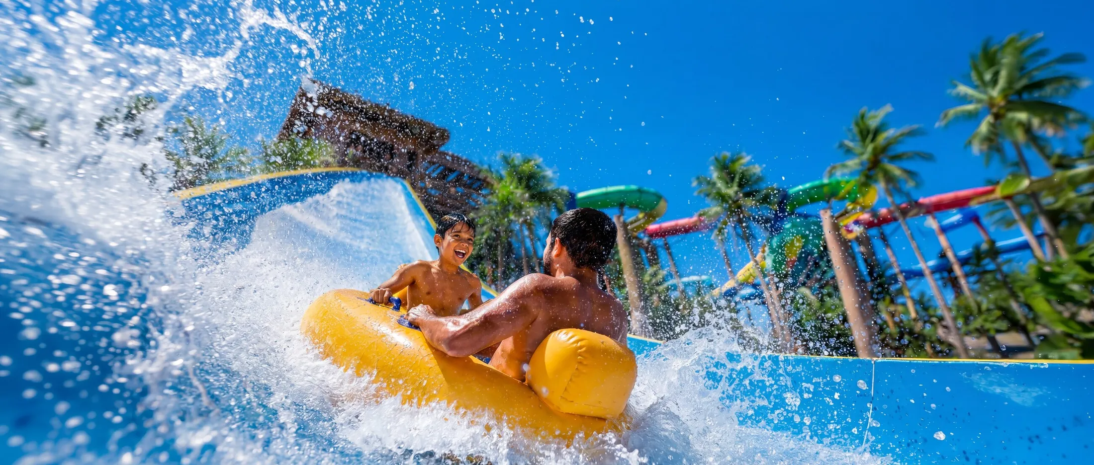 Pai e filho descendo de boia amarela em um toboágua do Aqua Park do Beach Park