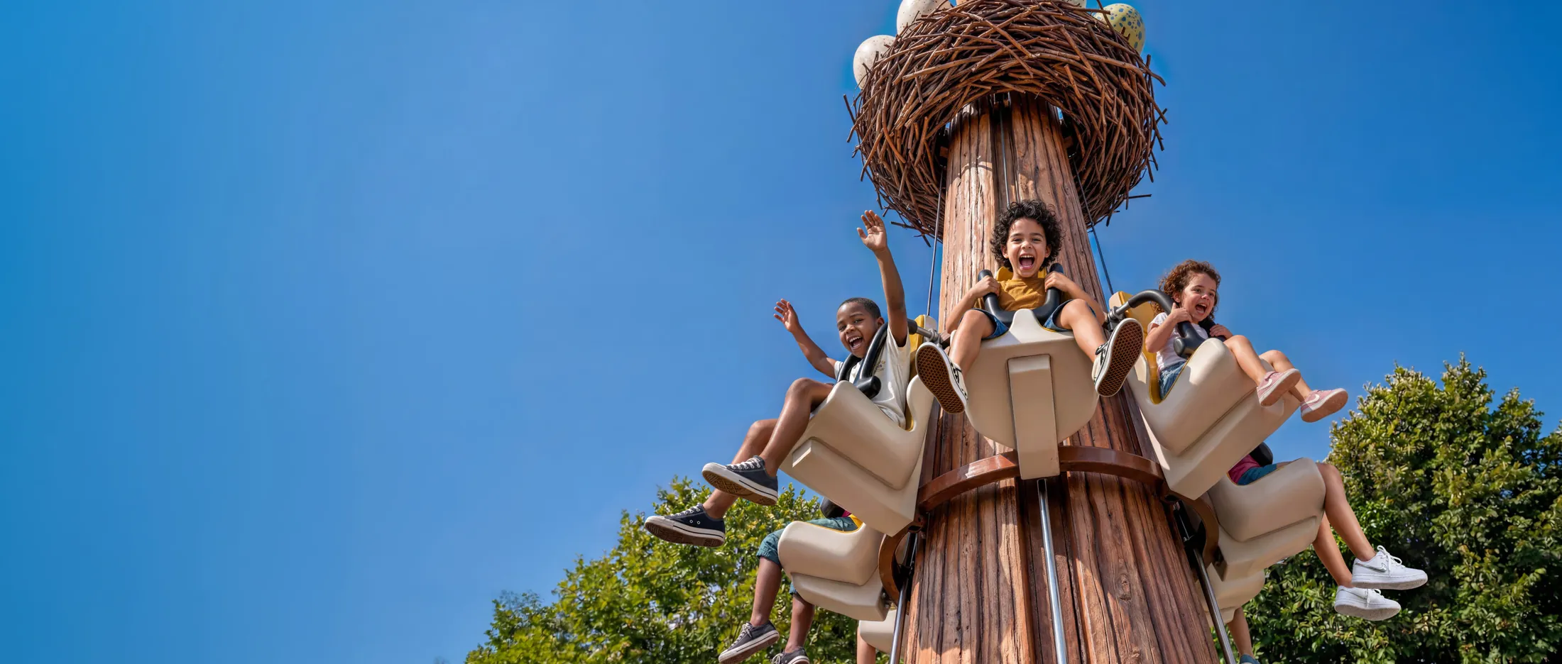 Crianças girando nos assentos da torre Ninho do Explorador, no Parque Arvorar